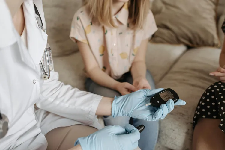 Zorgverlener meet bloedsuiker bij kind tijdens huisbezoek